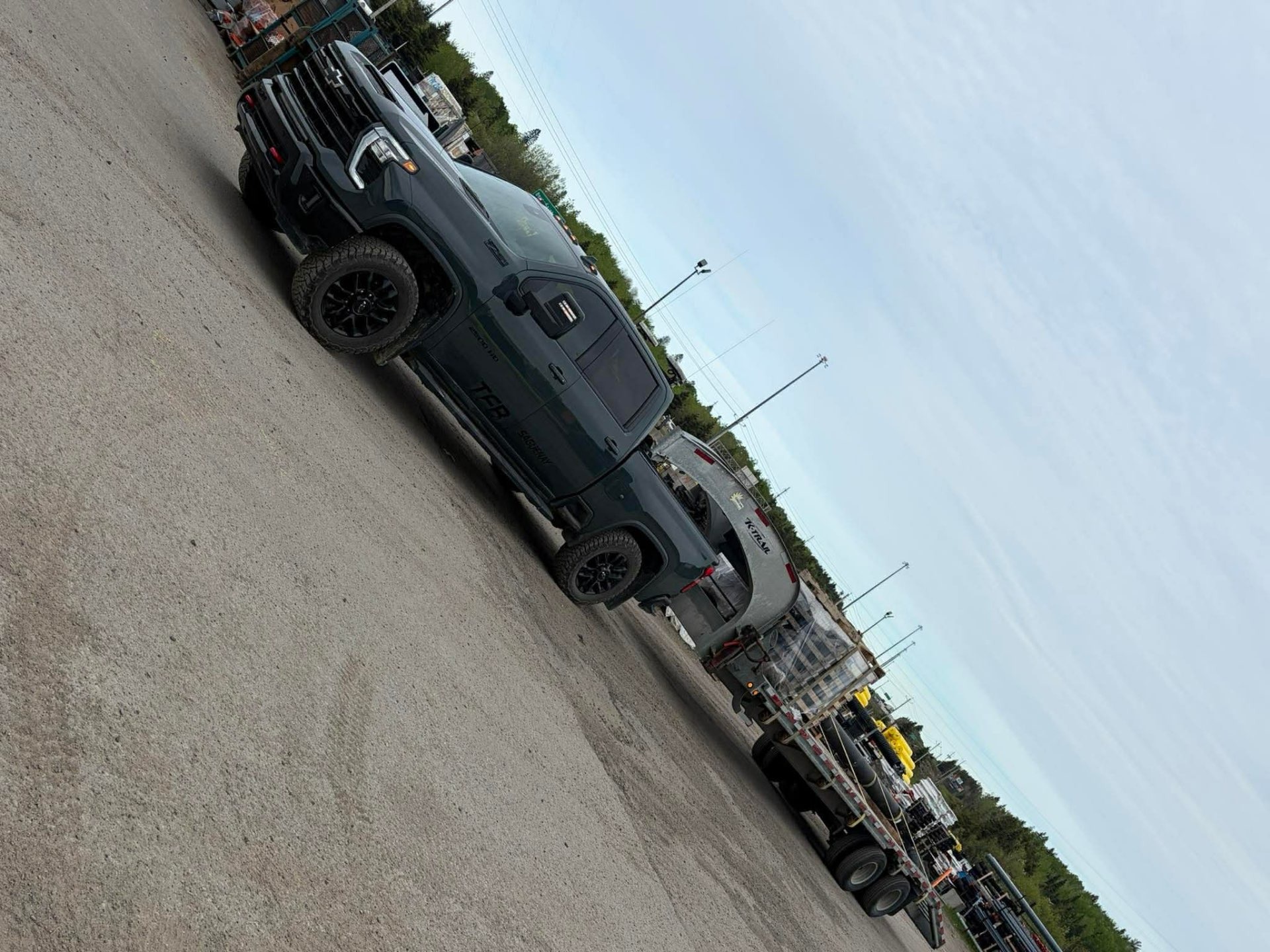 Pickup Chevrolet 2500HD TFB noir avec remorque K-Trail chargée à la cour