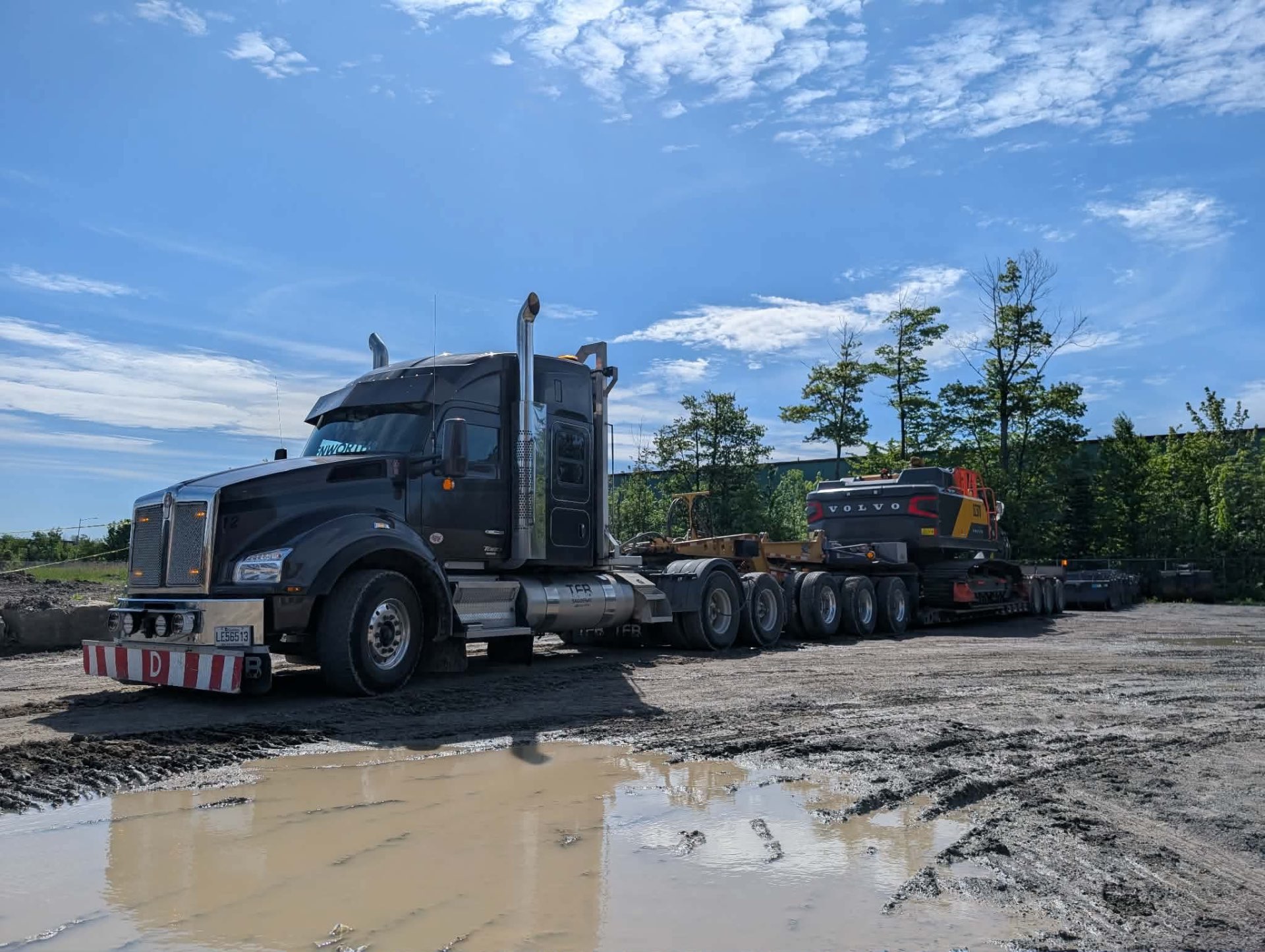 Kenworth noir TFB avec fardier multi-essieux chargé d'une excavatrice Volvo